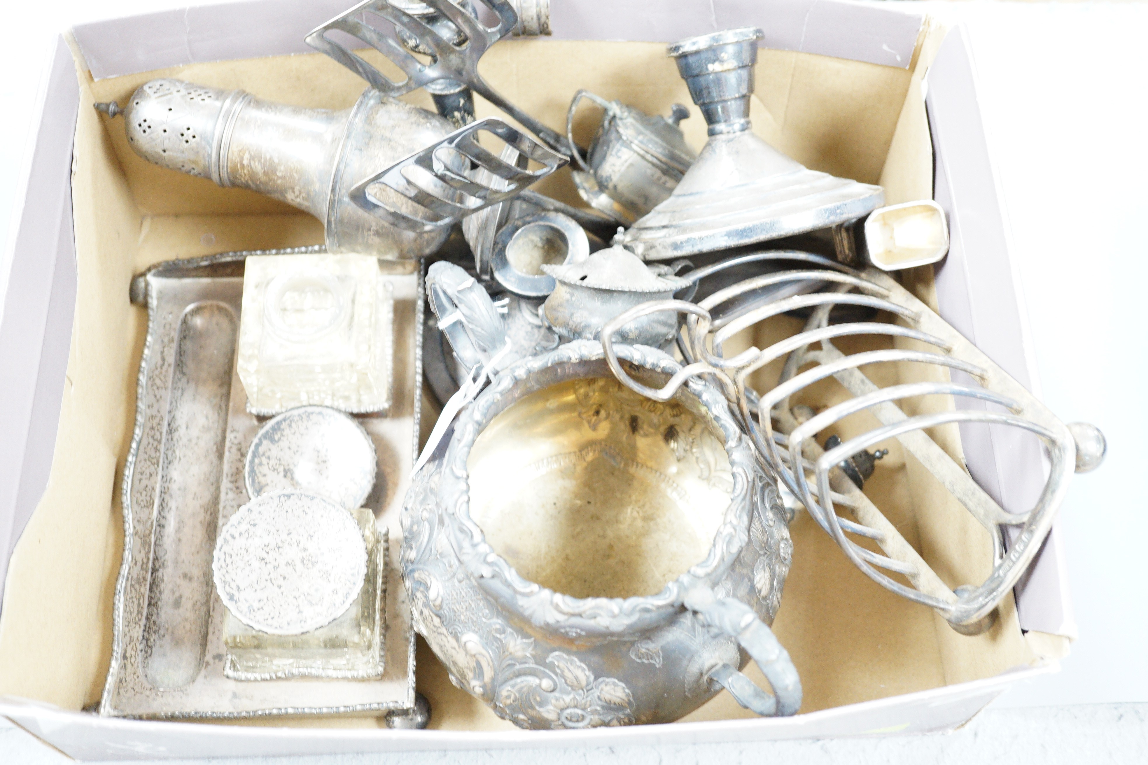 Assorted silver wares to include a George V toast rack, Birmingham, 1934, napkins rings, weighted dwarf candlesticks, cigarette case, condiments, an Edwardian desk stand and a Victorian Irish two handled sugar bowl jar,